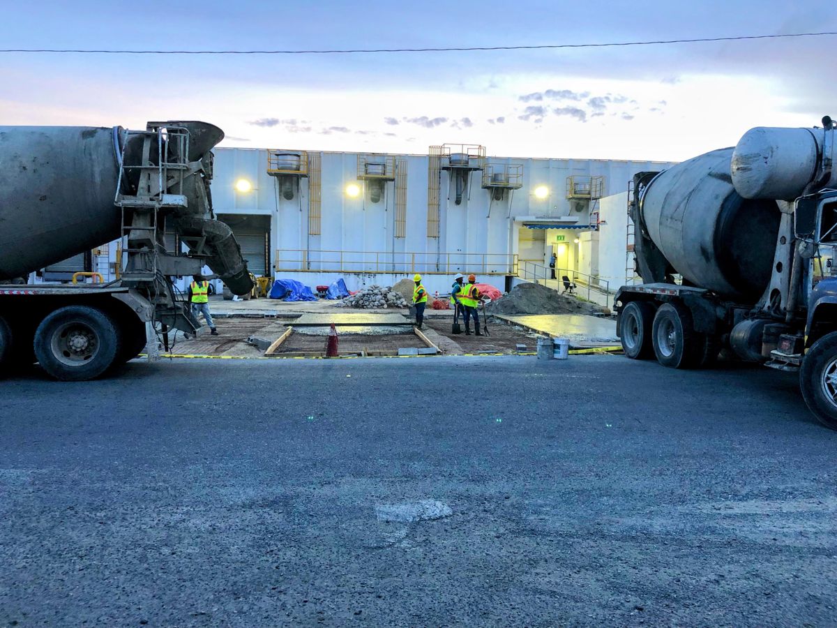 Vaciado de hormigón de la rampa para furgones en PIISA, Haina, con dos camiones mezcladores y el equipo en obra